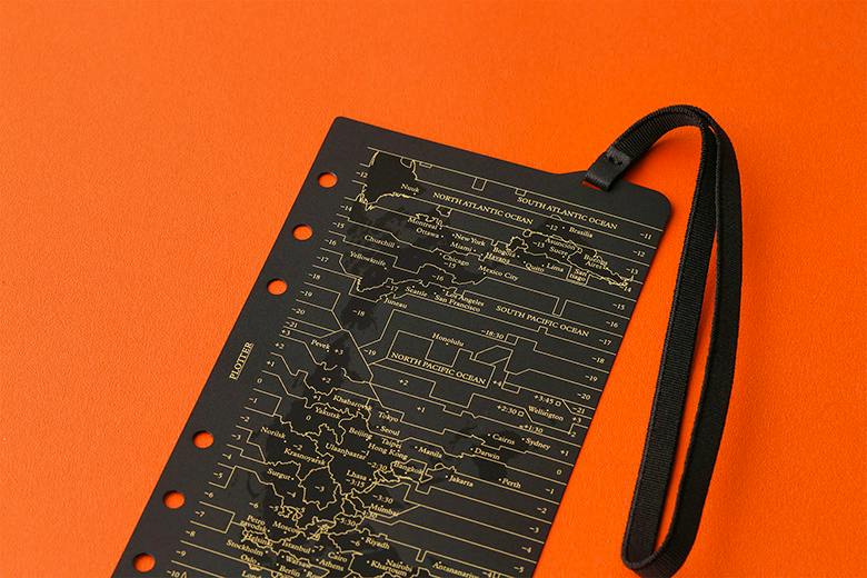 Black plastic Bible-size band lifter refill with printed map design, six binder holes, and a black elastic strap on an orange background.