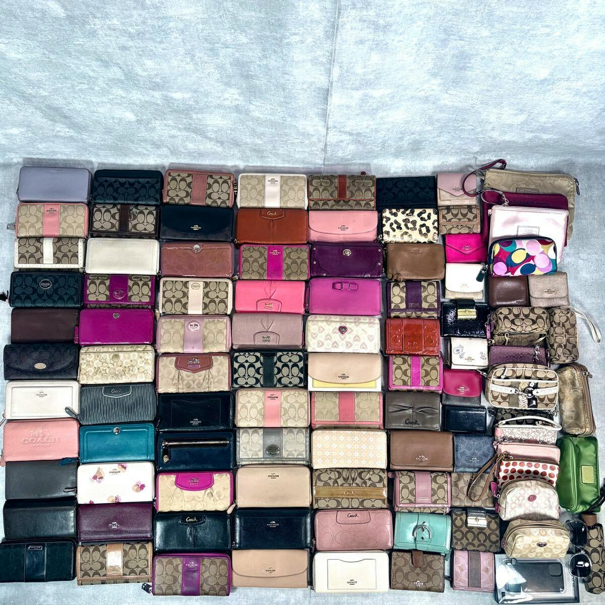 Top-down view of a large assortment of Coach wallets and pouches arranged in rows on a light background.