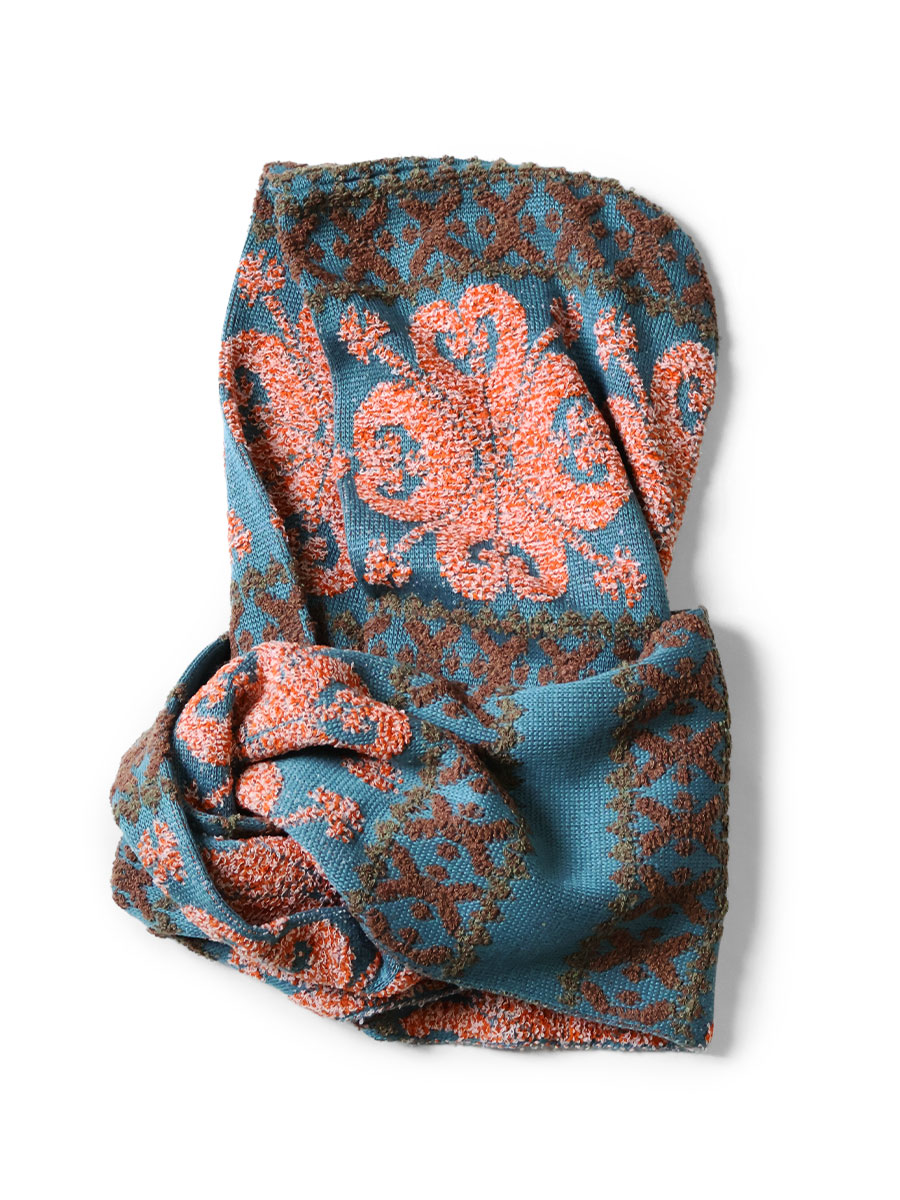 Folded blue jacquard wool scarf with orange floral motifs on a white background.