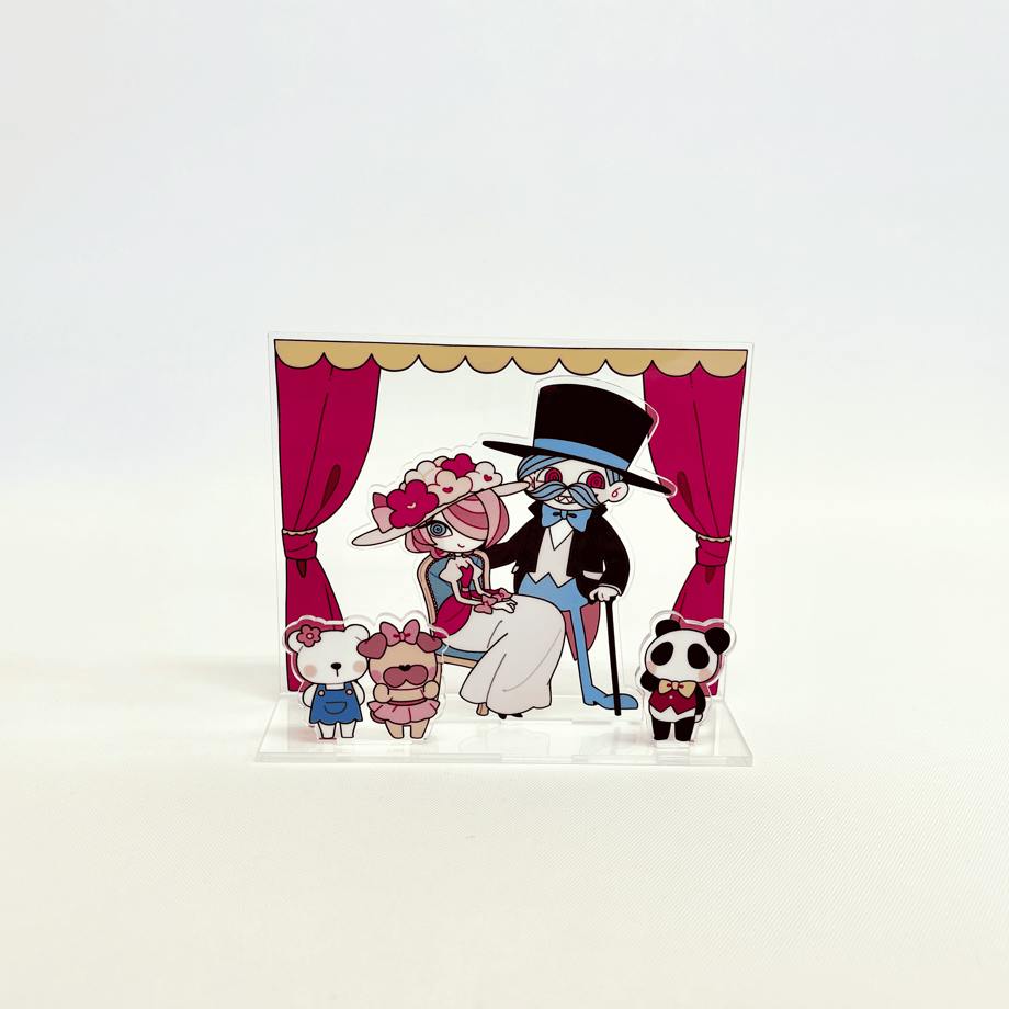 A clear acrylic stand diorama showing illustrated characters on a small stage with red curtains on a clear base.