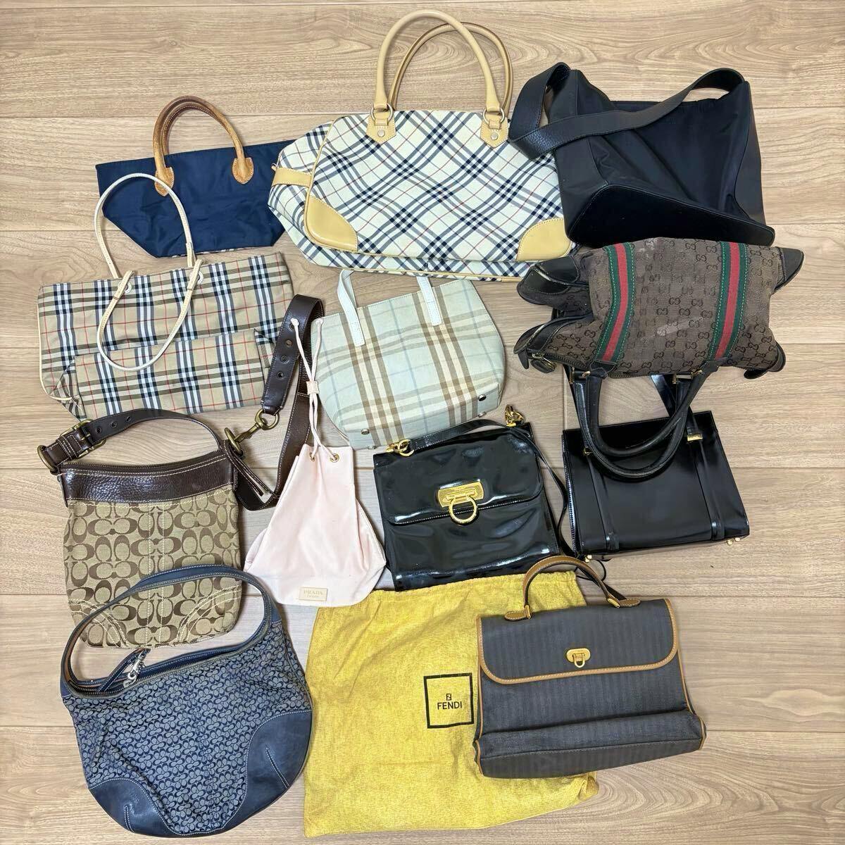Twelve assorted bags and pouches from designer brands laid out on a wooden floor.