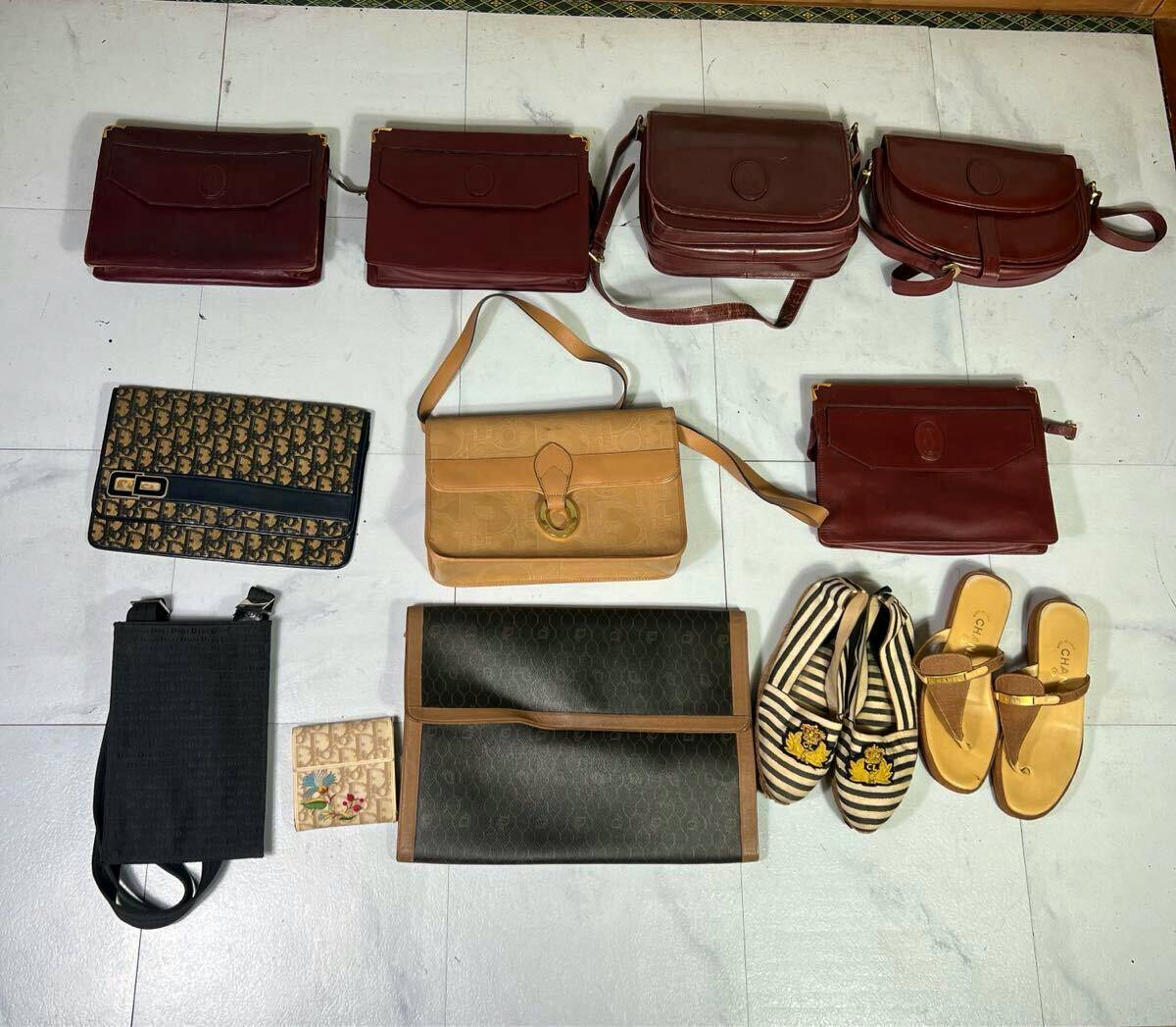 Top-down photo of the 12-piece lot laid out on a light floor showing multiple leather shoulder bags, a Dior-pattern clutch, wallets, and pairs of shoes.