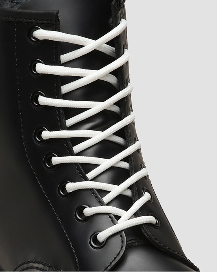 Close-up of white shoelaces threaded through the eyelets of a black boot.
