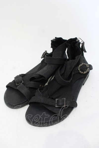Pair of black wrap leather sandals with snake-shaped buckles shown on a white background.
