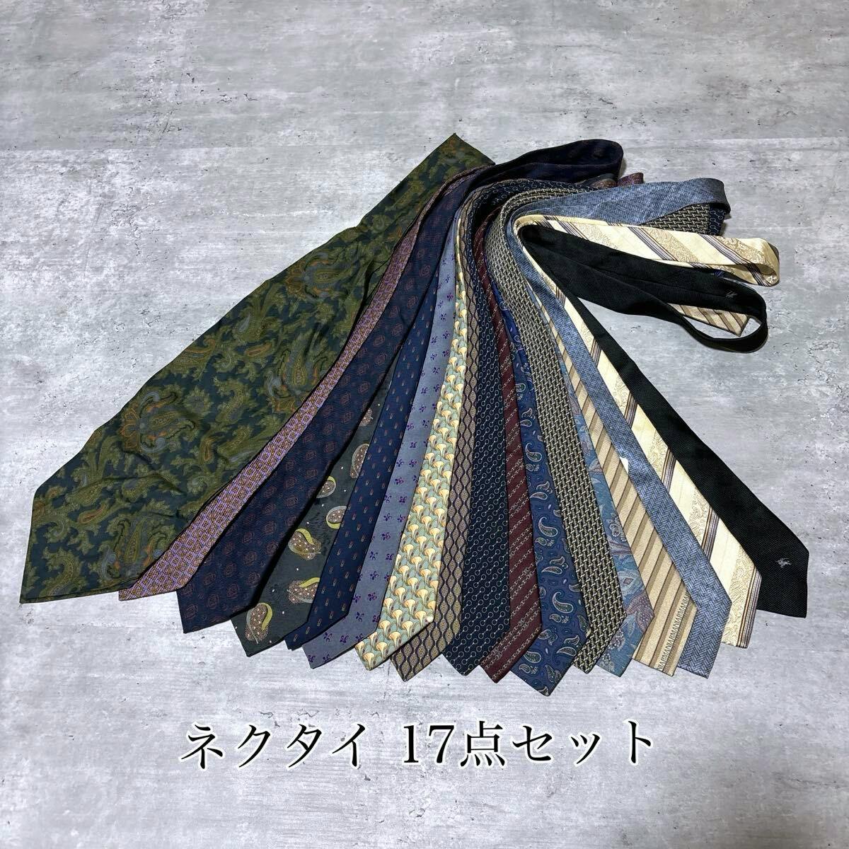 A fanned arrangement of 17 men's silk neckties laid out on a gray surface.