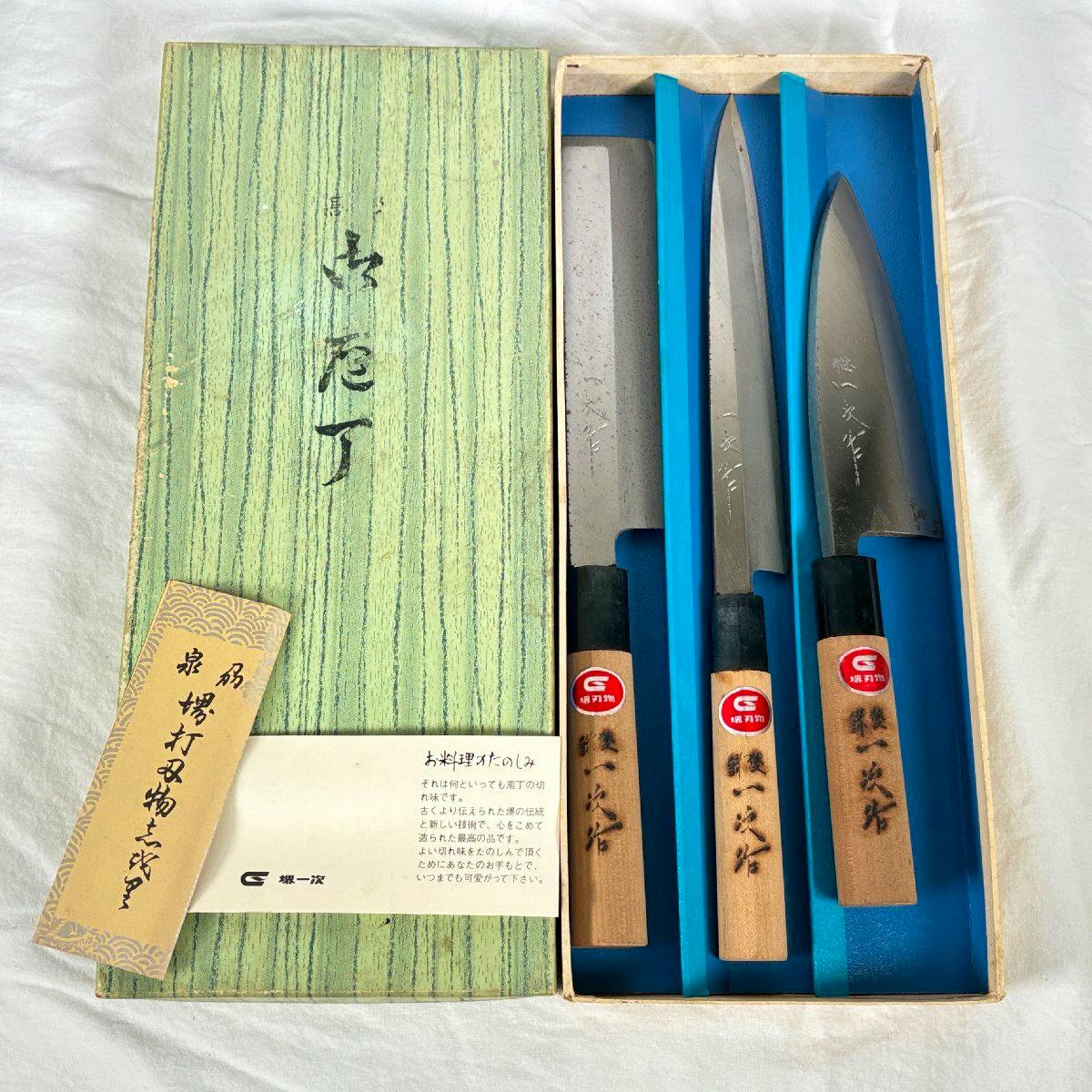 Three Japanese kitchen knives in a presentation box with wooden handles and included paperwork.