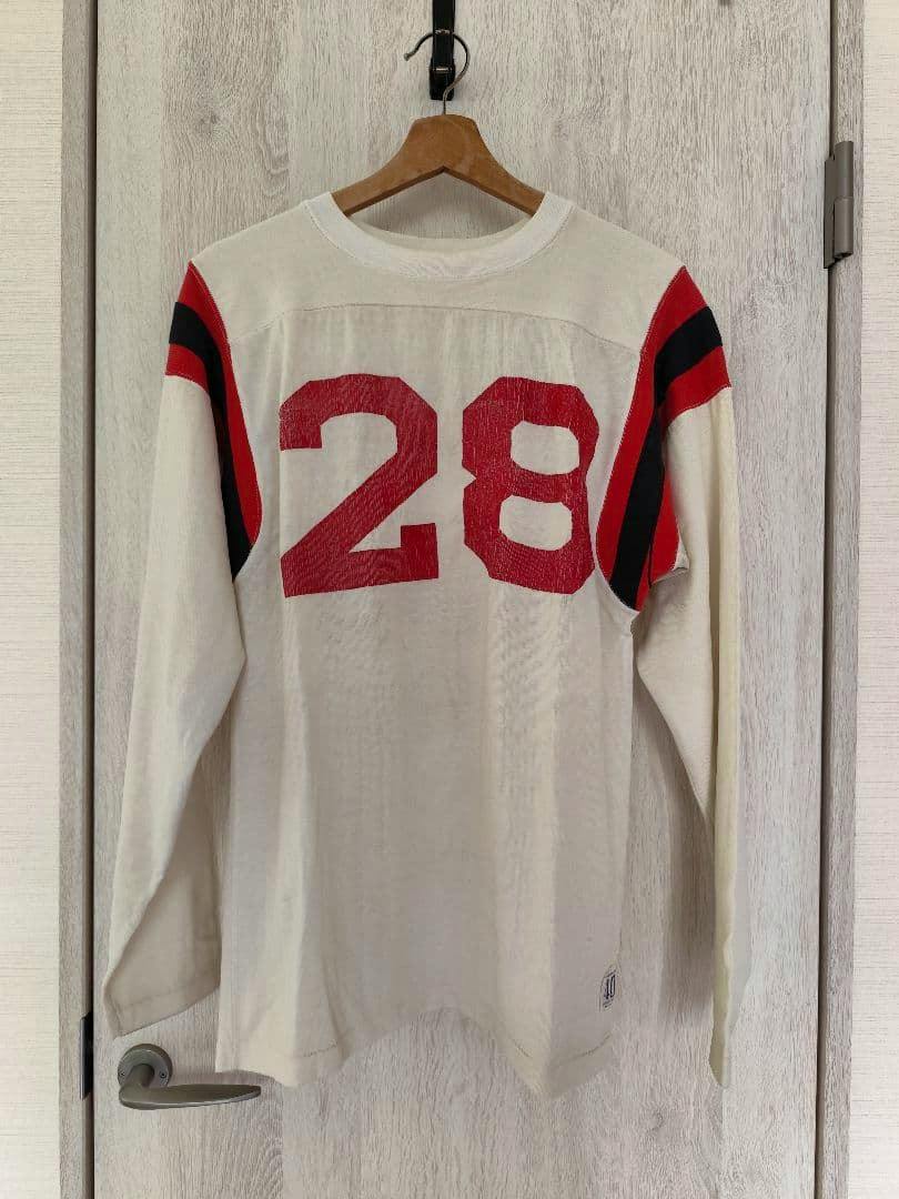 Vintage Champion men's white football shirt with red number 28 on the back and red-and-black sleeve stripes hanging on a hanger.