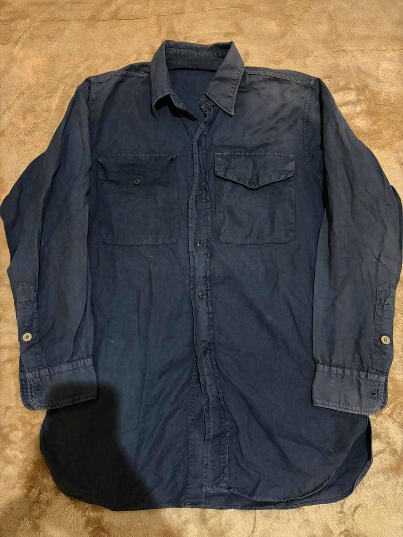 Front view of a black cotton men's work shirt laid flat showing the collar, button placket, and two chest pockets.