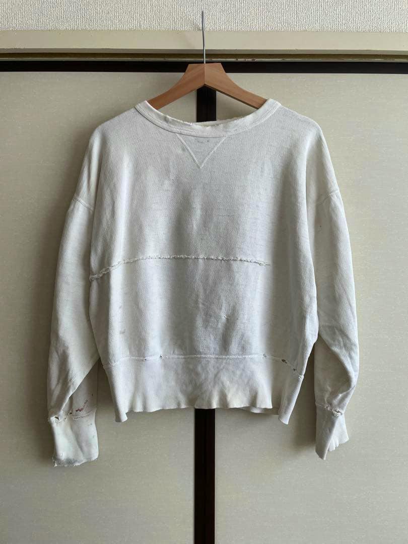 Off-white vintage men's cotton sweatshirt hanging on a wooden hanger against a beige background.