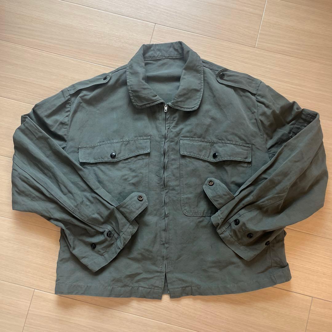 Green cotton men's pilot/flight jacket laid flat showing front pockets, zipper, collar, and long sleeves.