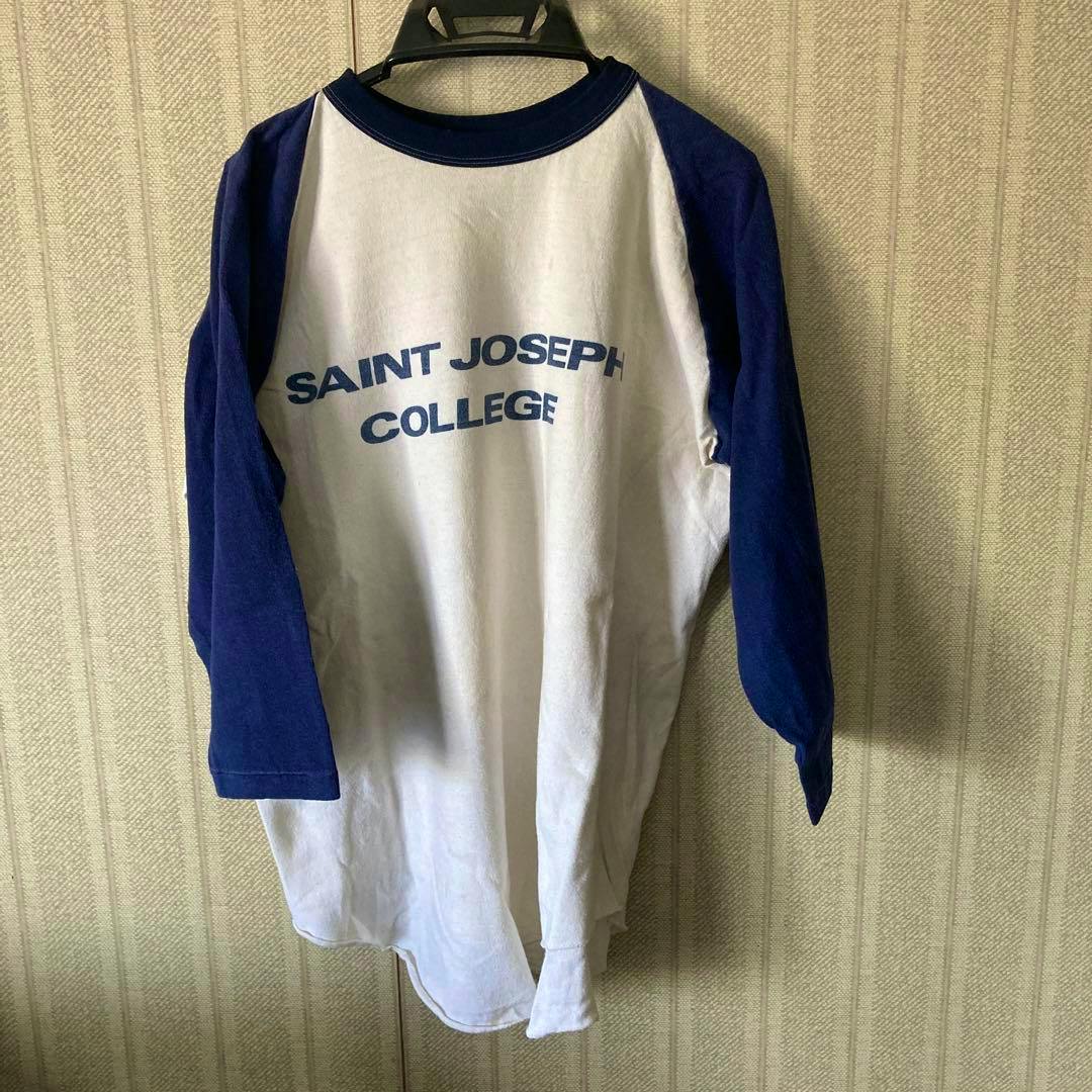 Front of a vintage raglan cotton t-shirt with white body, blue sleeves, and “SAINT JOSEPH COLLEGE” printed on the chest.