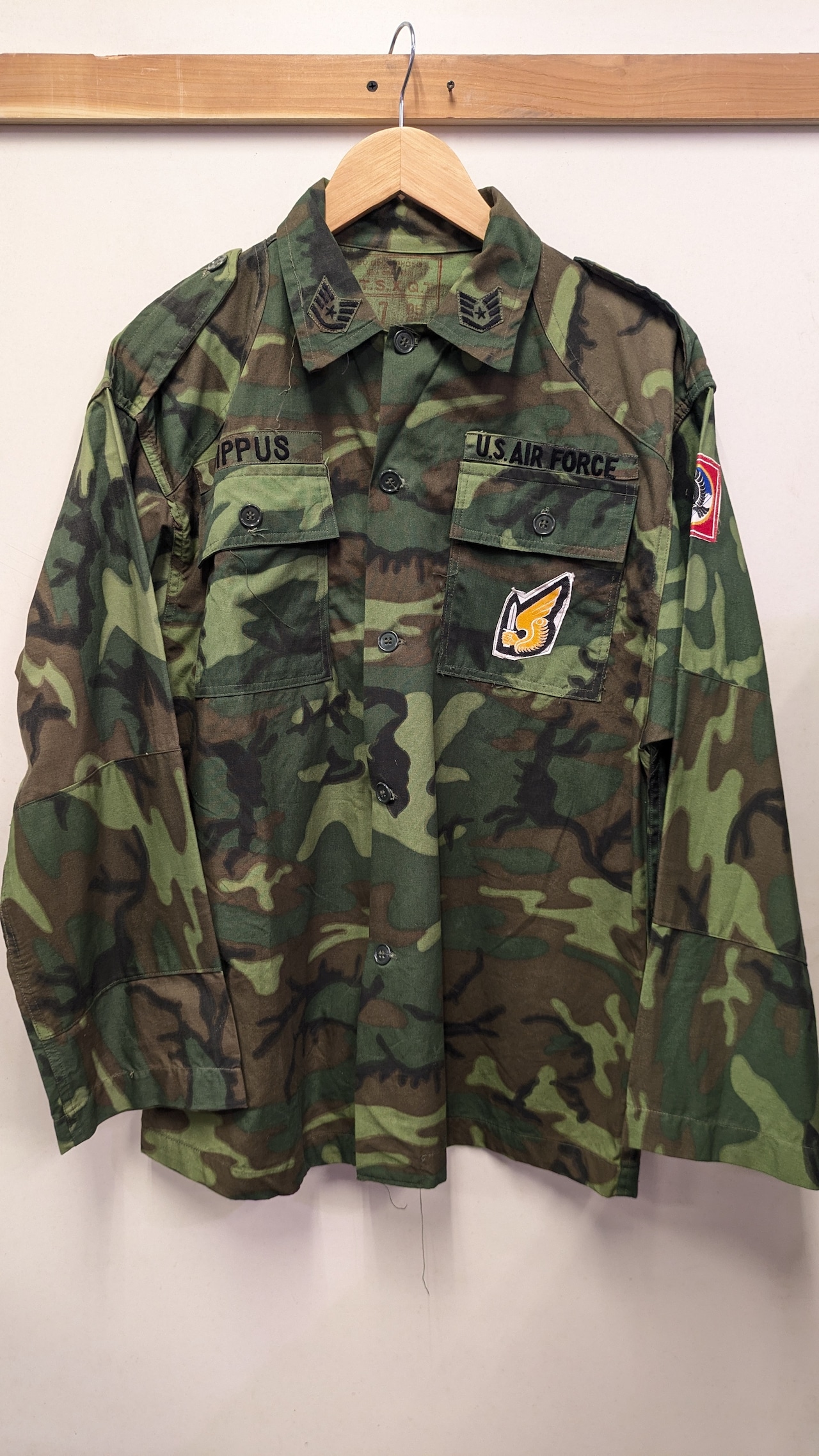 Front view of a green ERDL camouflage US Air Force men's jacket hanging on a wooden hanger.