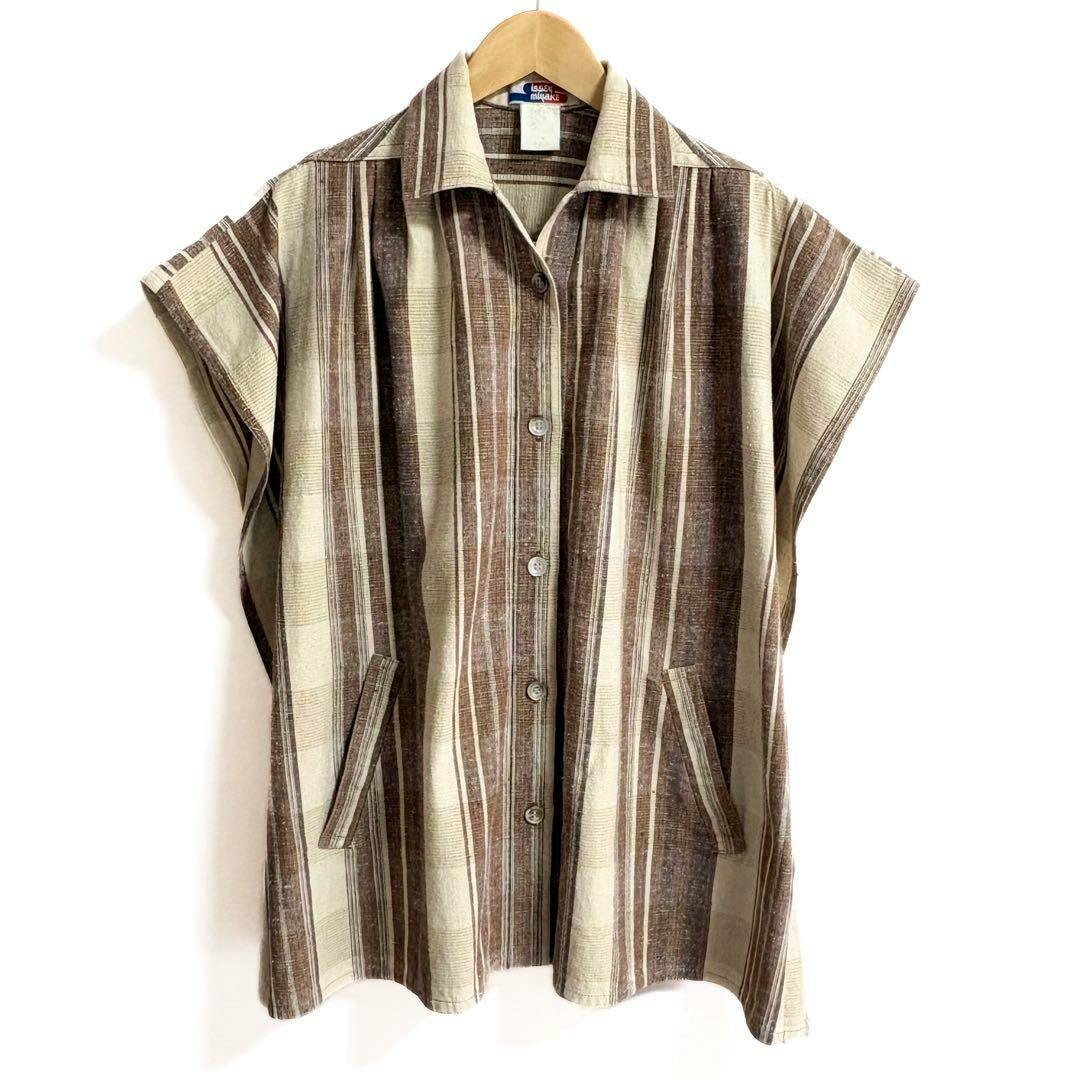 Front view of a women's Issey Miyake brown and beige striped cotton button-up shirt with short sleeves hanging on a wooden hanger.