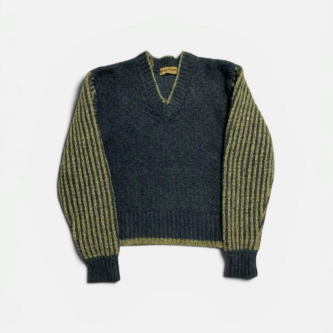 Flat-lay photo of a women's V-neck wool sweater with a dark gray body and green-striped sleeves.