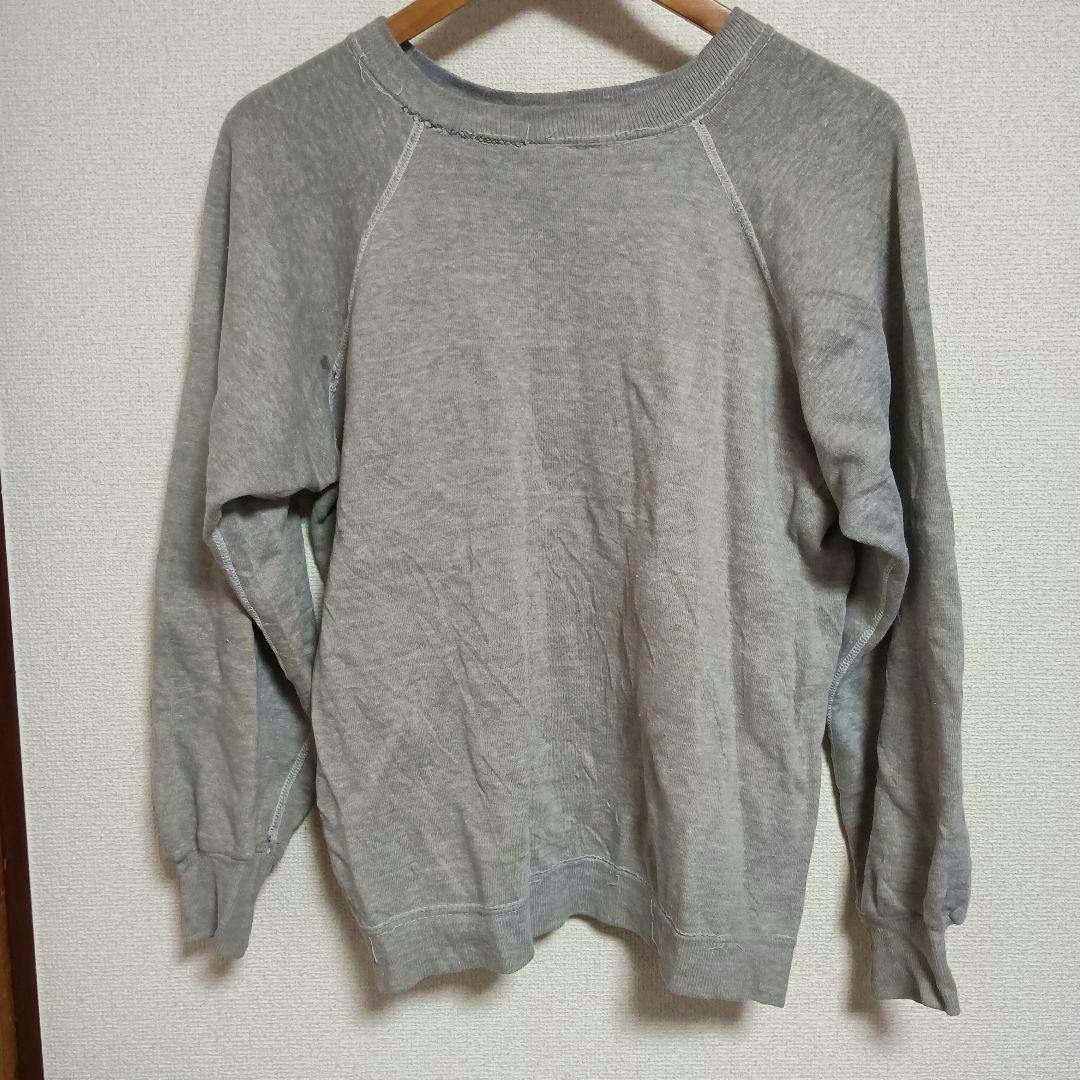 Gray raglan long-sleeve cotton sweatshirt hanging on a wooden hanger against a light wall.