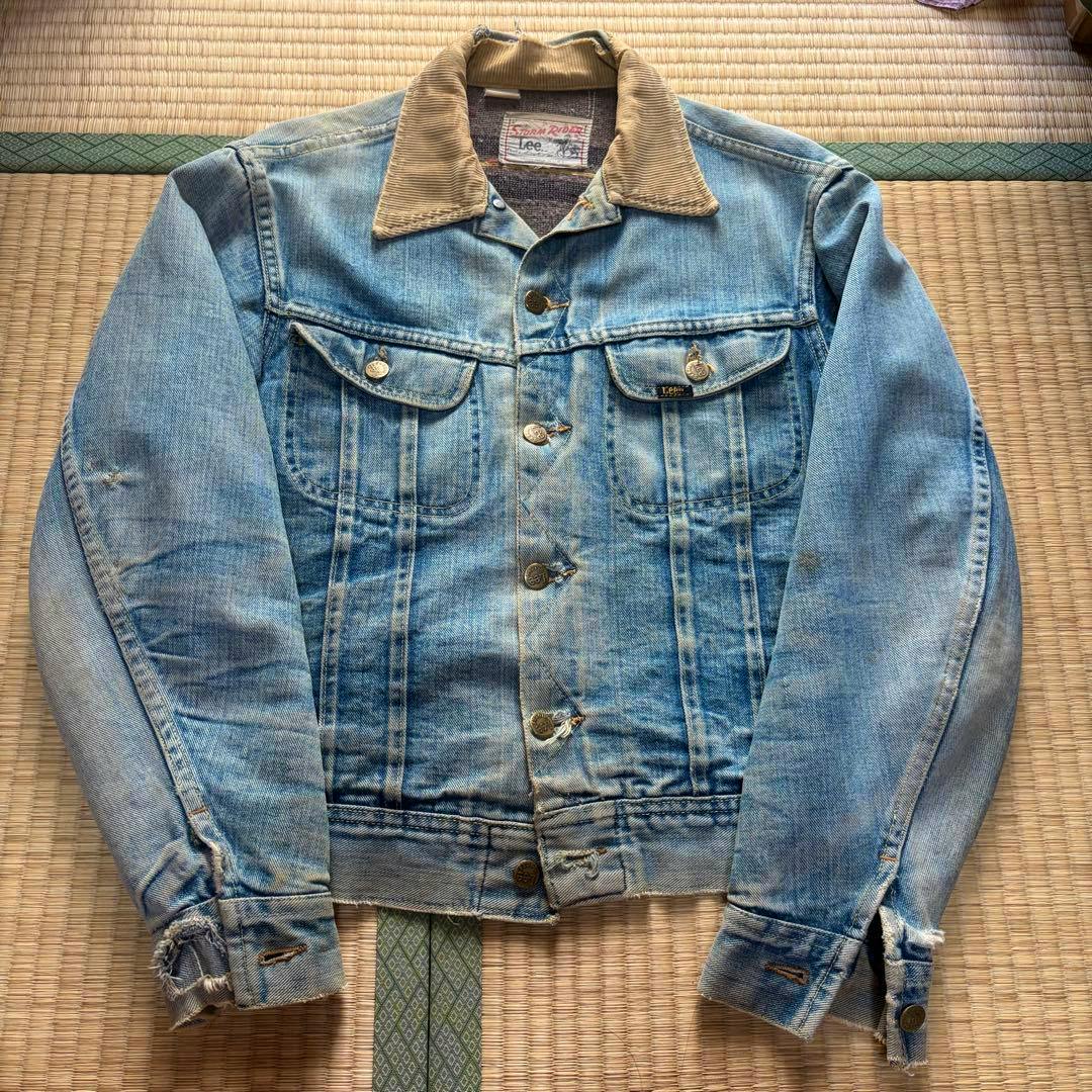 Front view of the men's 70s Lee Storm Rider jacket laid flat showing a denim body, corduroy collar, metal buttons, and visible wear and fraying.