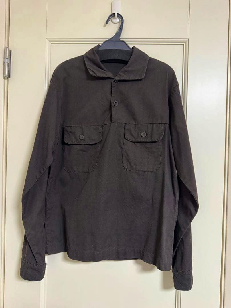 Front view of the vintage pullover shirt hanging on a hanger, showing the collar, button placket and two chest flap pockets.