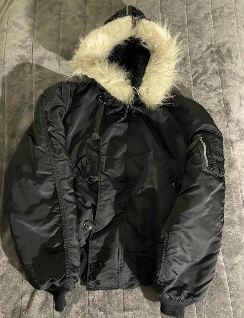 Black Alpha N-2B fur-lined jacket with hood and cream fur trim laid flat.