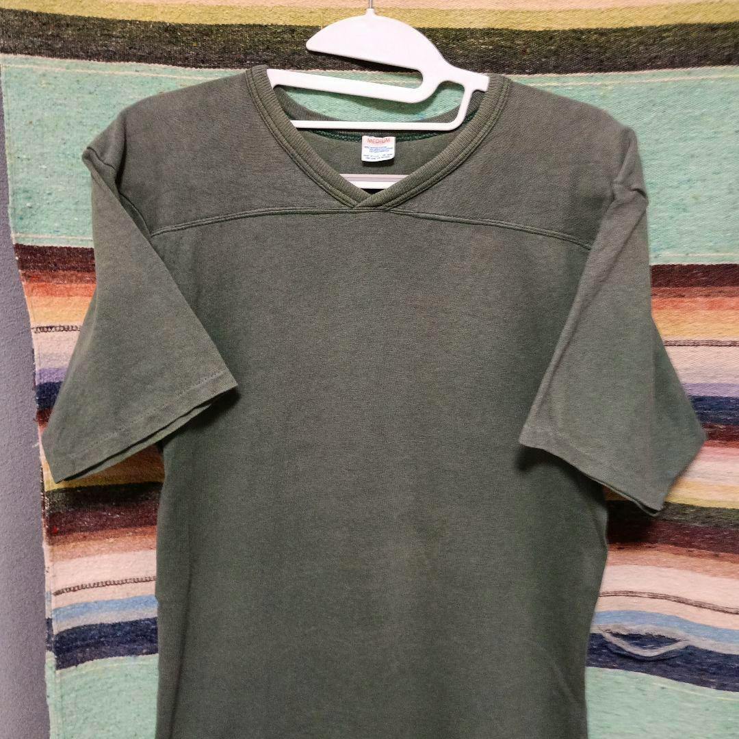 Front view of a green 1980s Champion football-style men's cotton T-shirt hanging on a hanger, showing the V-neck and short sleeves.