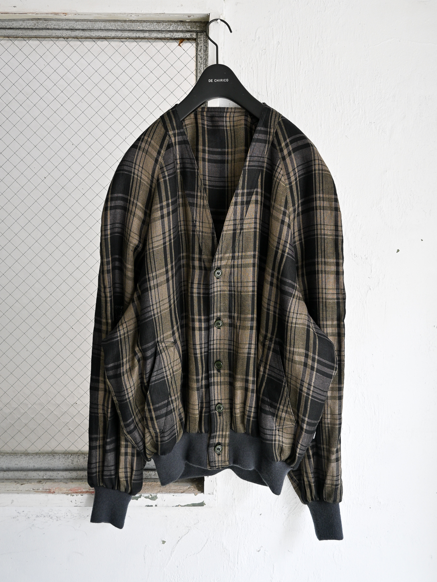 Front view of an 80s Italian women's cotton plaid jacket hanging on a black hanger against a white wall.