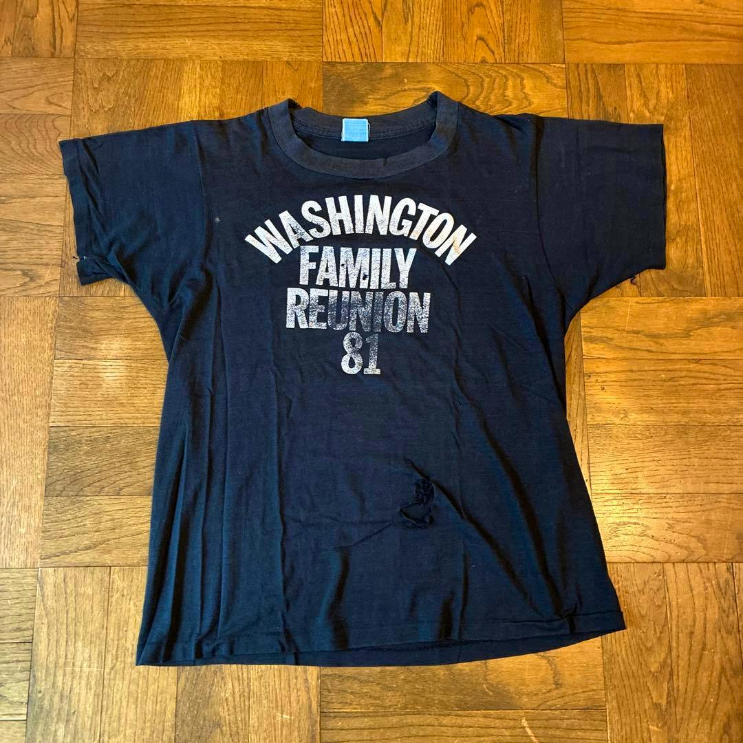 Black men's shirt laid flat on a wooden floor with "WASHINGTON FAMILY REUNION 81" printed on the front.