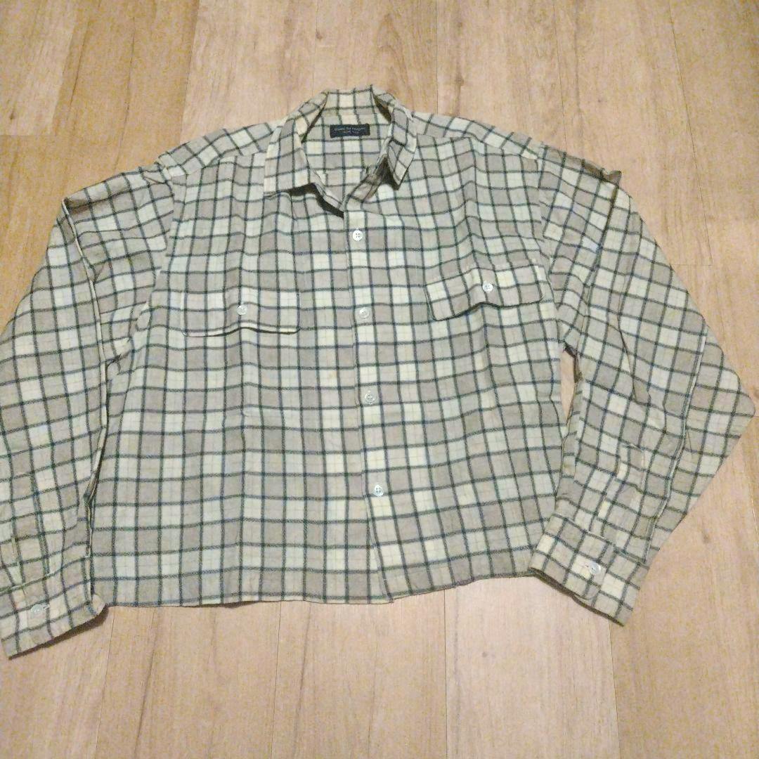 Light wool ombre checked shirt laid flat showing the front, collar, pockets, and buttons on a wooden floor.
