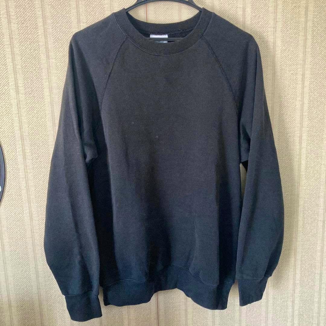 Front view of a black blank Lee sweatshirt hanging on a hanger against a patterned wall.