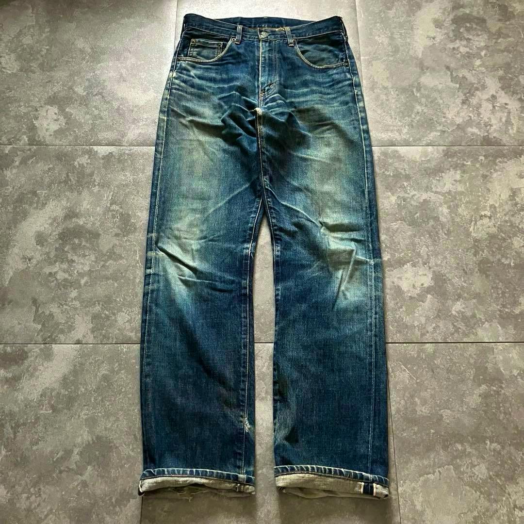 Front view of 90s Levi's 502xx men's jeans (W32) laid flat on a tiled floor showing fading and rolled cuffs.