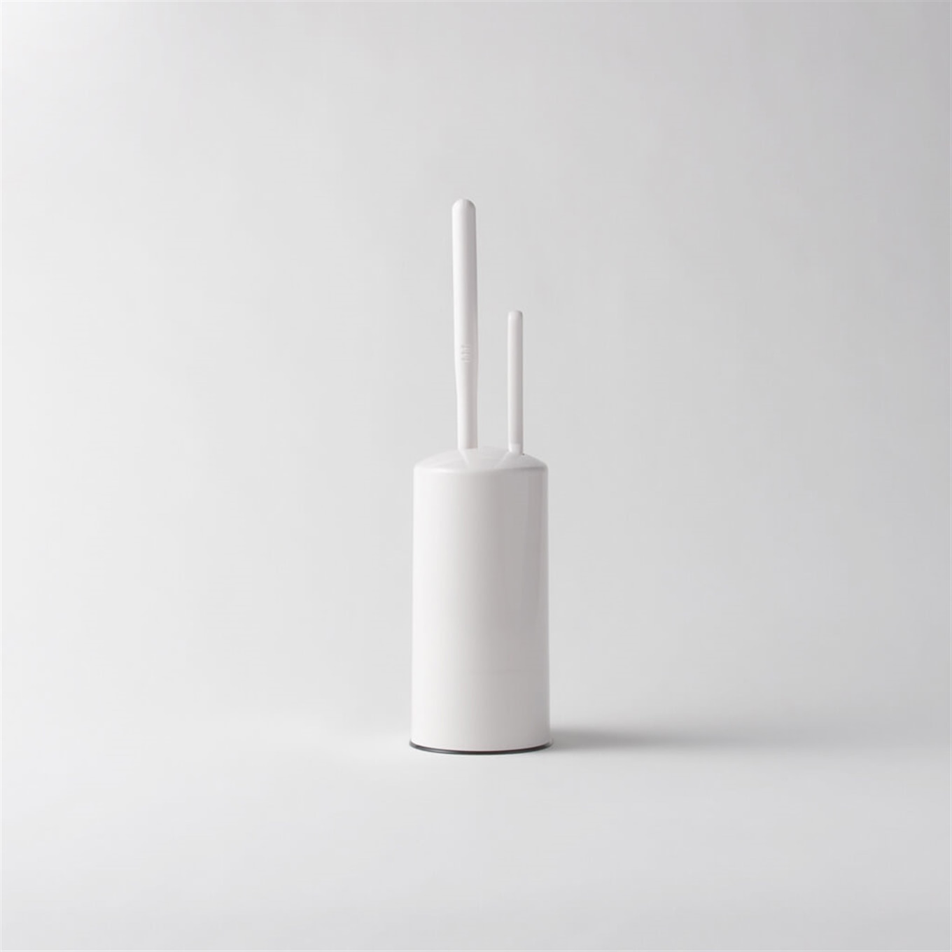 White cylindrical toilet brush holder with two brush handles visible on a plain background.