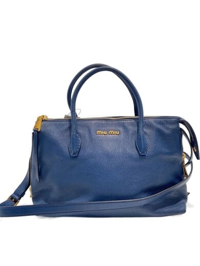 Front view of a blue cow leather 2-way handbag with top handles, shoulder strap, and gold hardware.