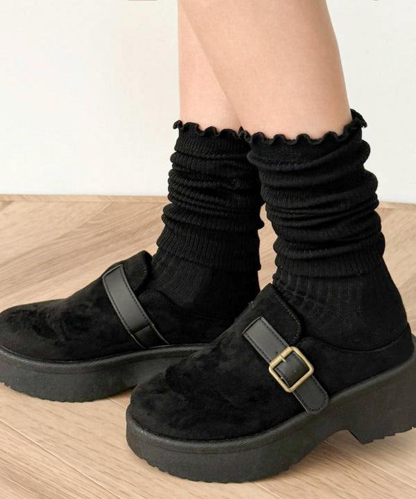 Black women's high socks with ribbed texture and ruffled (merrow) top shown on a model wearing black platform shoes.