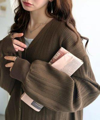 Model wearing a brown ribbed 2-way tuck knit cardigan shown from chest to hips while holding a book.