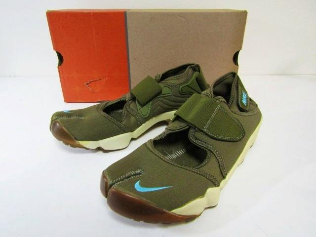 Olive-green Nike Air Rift shoes (pair) with blue Swoosh visible, photographed with the shoe box behind them.