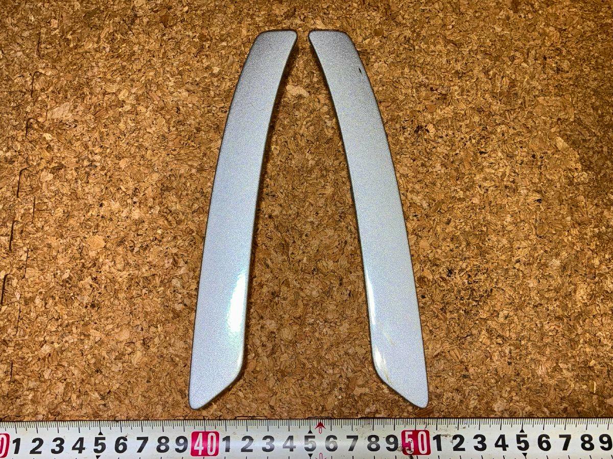 Two silver door inner grip panels (left and right) for a Copen L880K displayed on a cork background with a measuring tape.
