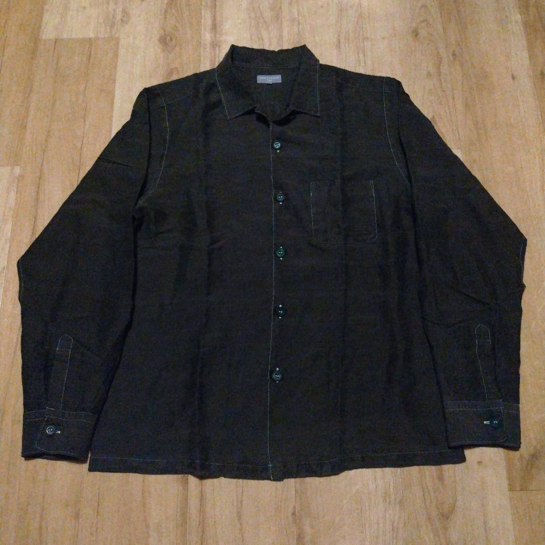 Dark open-collar men's cotton shirt laid flat showing the front, buttons, and chest pocket.