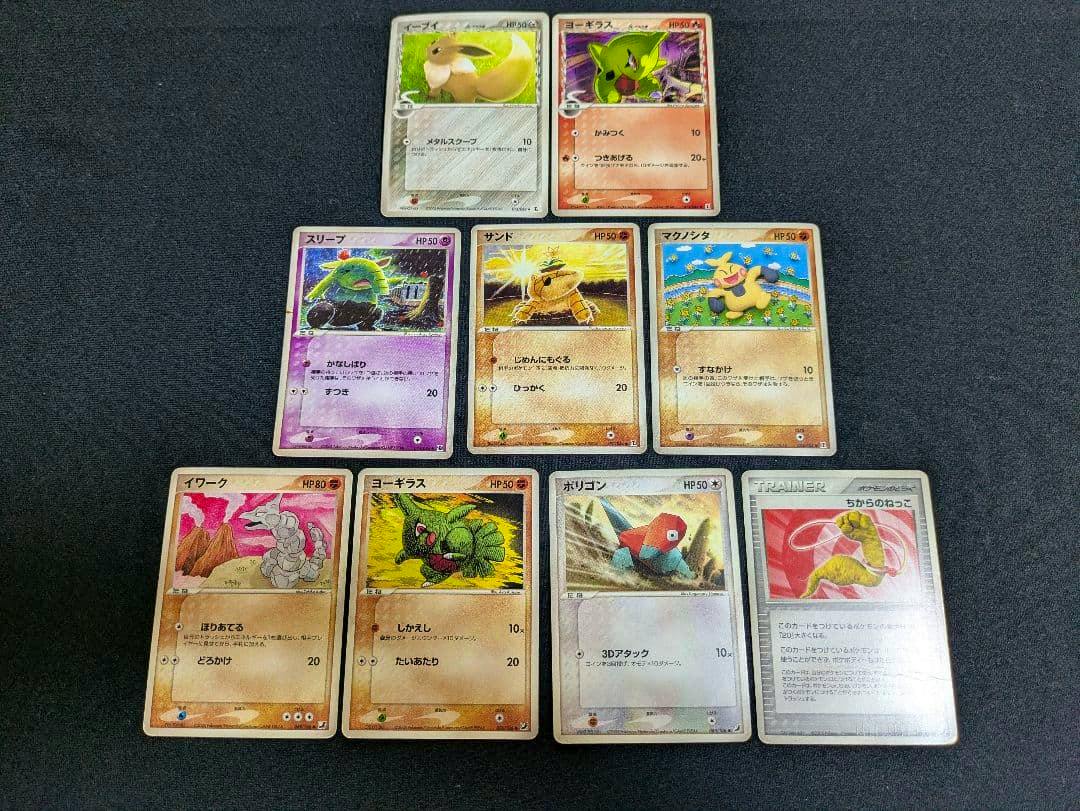Nine 2005 Pokémon Delta species trading cards (fronts) including Eevee and Yogirasu arranged on a dark surface.
