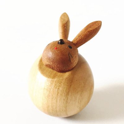 Photo of a wooden round rabbit ornament with carved ears and painted facial features on a white background.