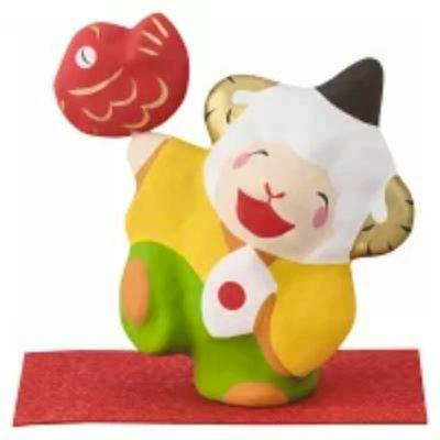 Colorful sheep zodiac figure (未) with a white head and horns, holding a red sea bream while standing on a red rectangular mat.
