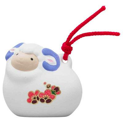 A white sheep-shaped charm with blue horns, a red hanging cord, and a small floral decoration on its body.