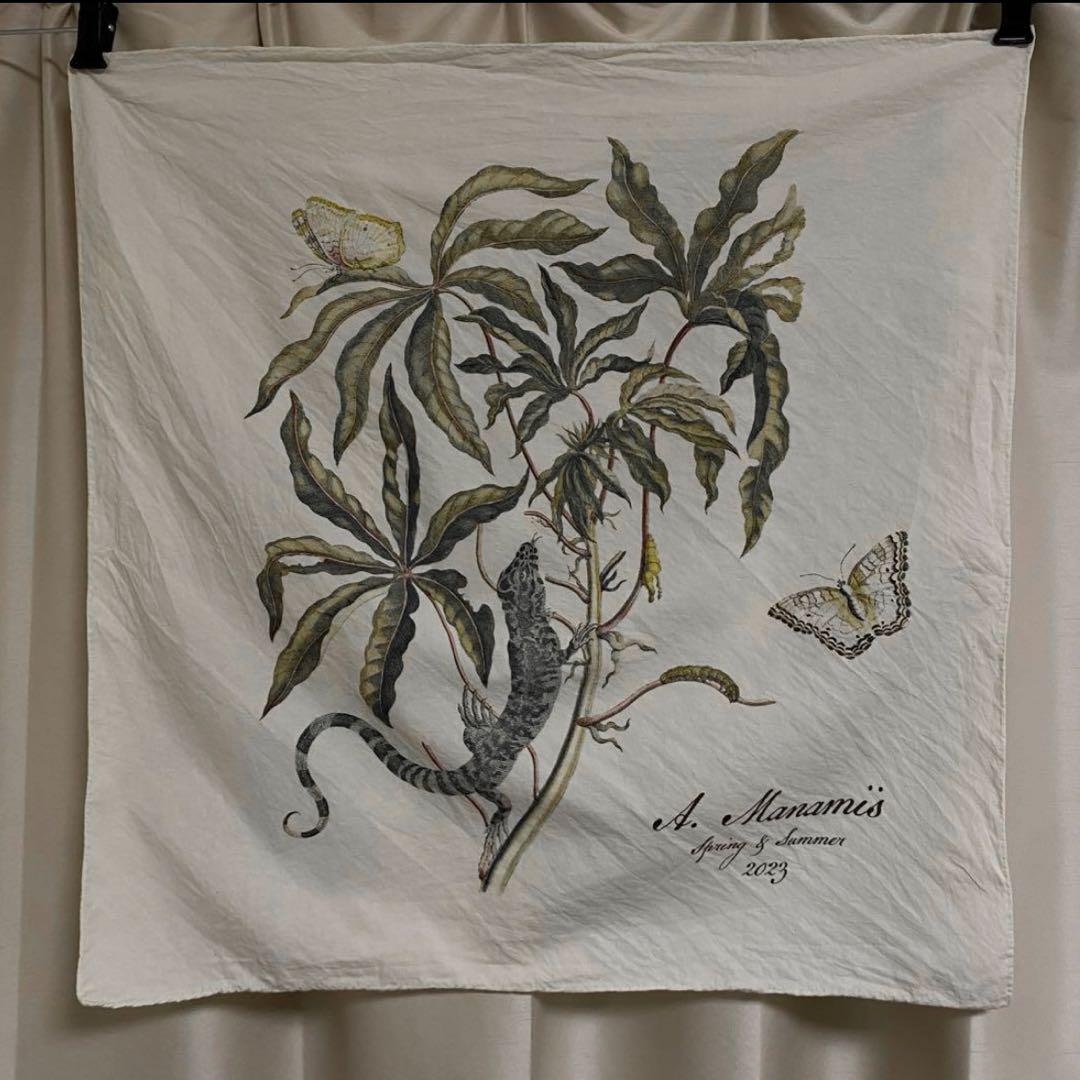 A square white cotton bandana with a botanical print showing a lizard, butterflies, and the text "A. Manamis Spring & Summer 2023".
