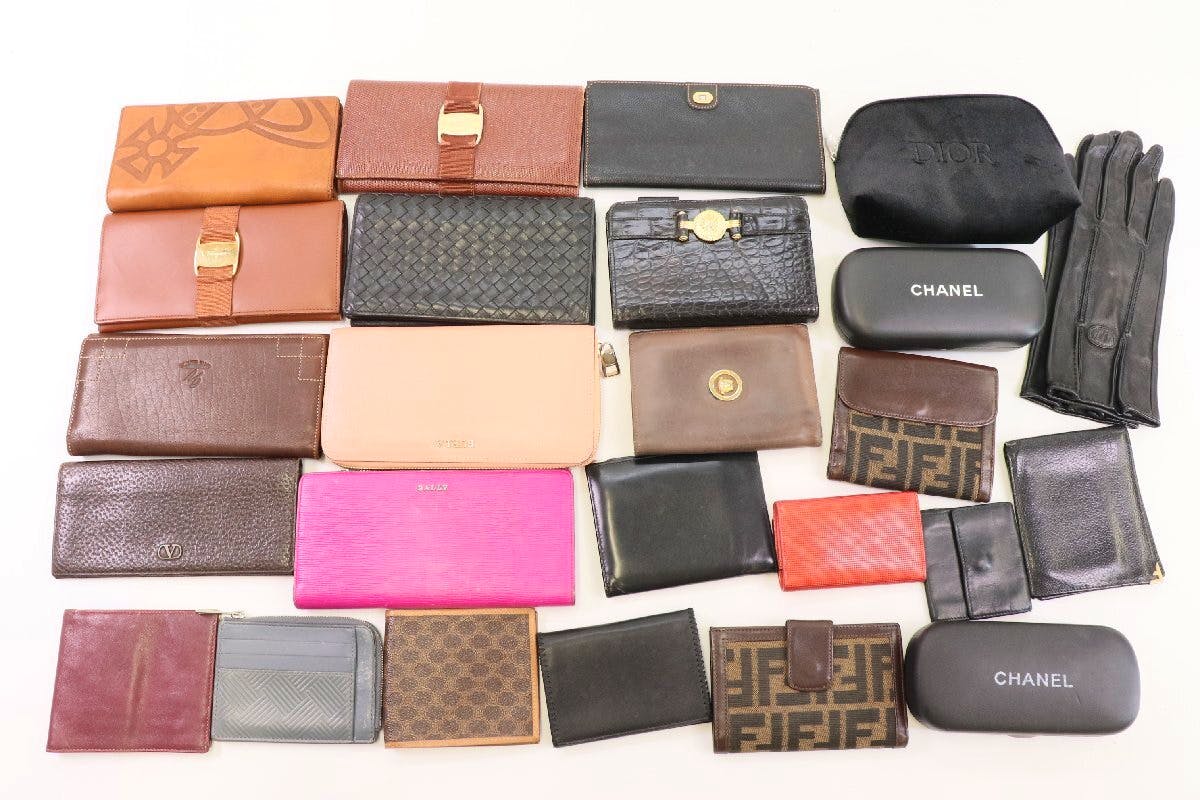 Assorted wallets, pouches, gloves, and other small fashion accessories arranged on a white background.