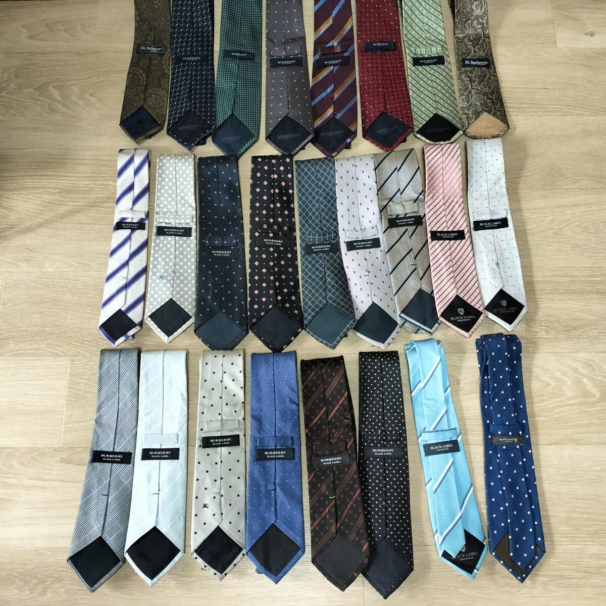 Flat lay of 25 silk neckties arranged in rows on a wooden floor, showing various Burberry and Black Label designs.