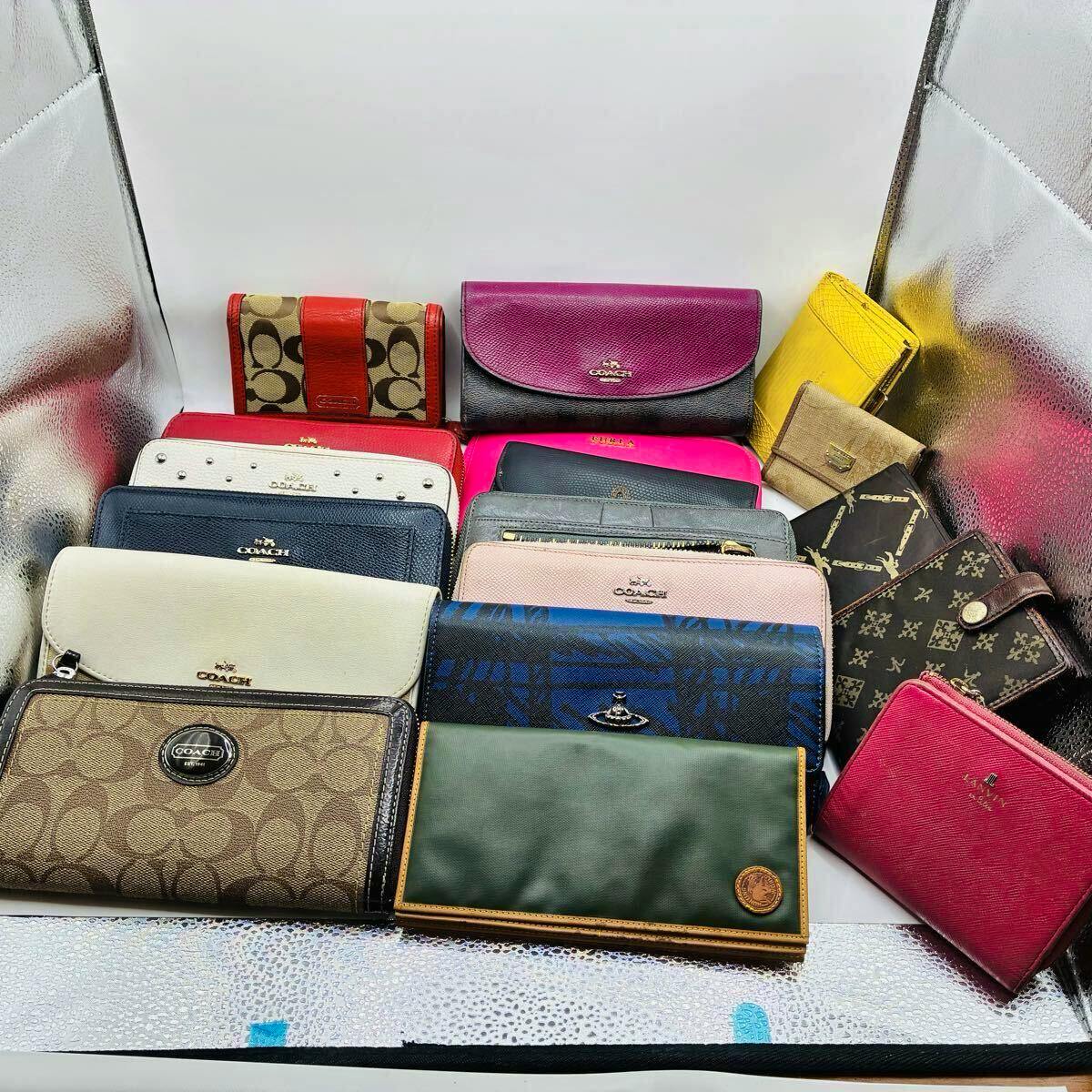 A collection of wallets and small bags, including COACH items, arranged on a reflective backdrop.