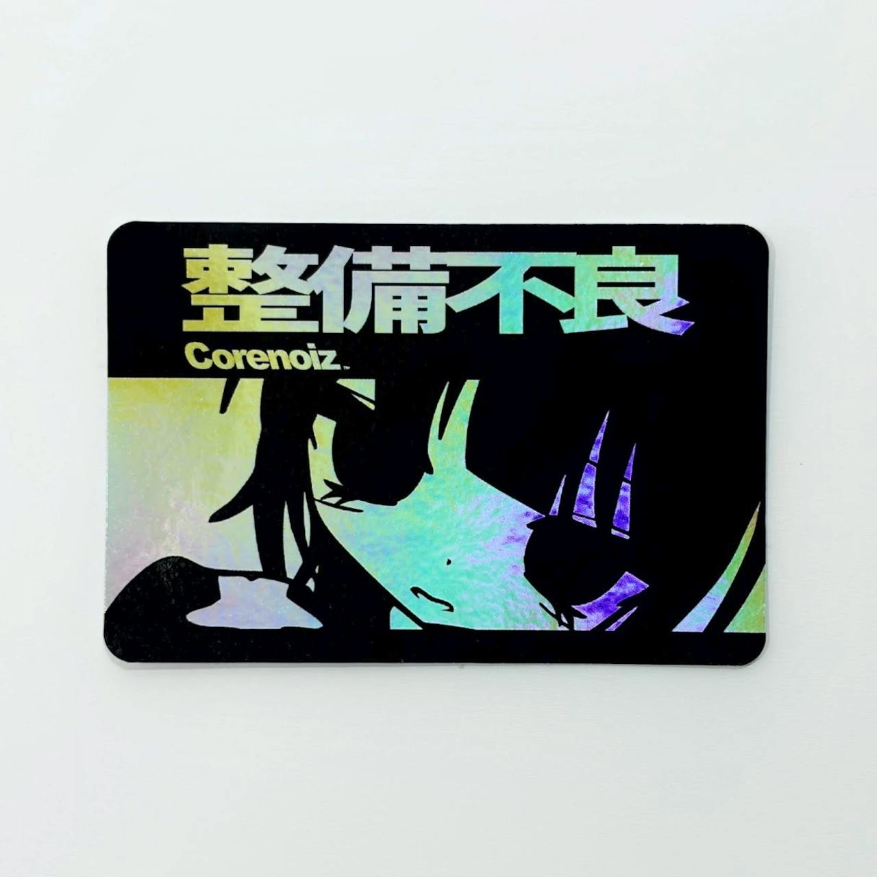 A rectangular holographic plastic sticker showing Japanese text "整備不良" and a stylized anime face on a black background.