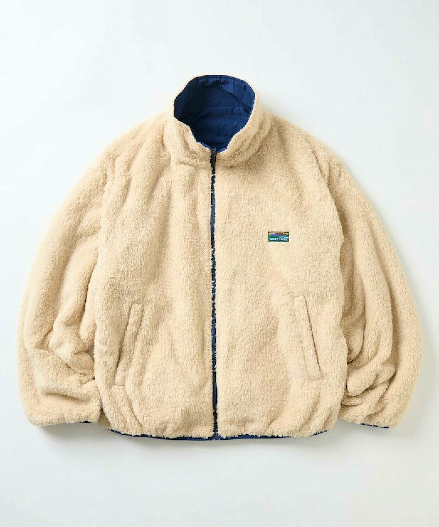 Beige sherpa fleece reversible liner jacket laid flat showing stand collar, front zipper, and navy inner lining.