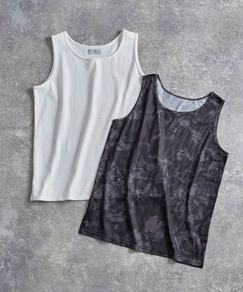 Two layered tank tops laid flat, showing a white cotton inner tank with a dark patterned mesh outer tank.