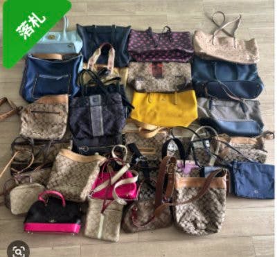 Photo of many Coach bags and totes arranged on a floor, showing multiple leather and signature canvas styles.