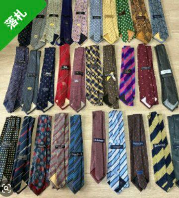 Thirty polyester neckties laid out in rows on a flat surface showing various colors and patterns.