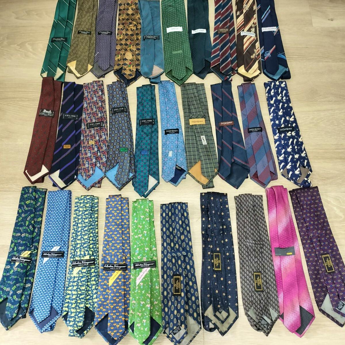 Top-down photo of a large set of men's neckties laid out on a wooden floor, showing many patterned and solid ties.
