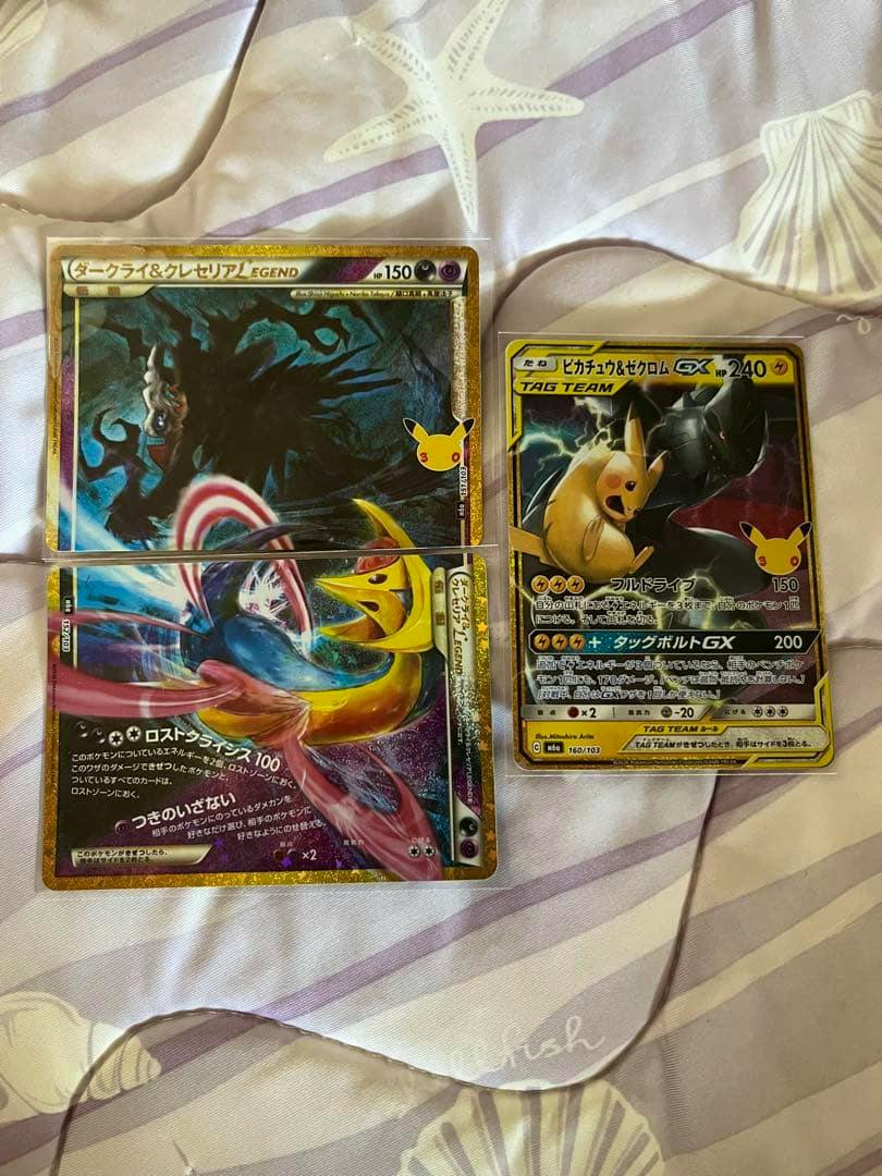 Two Pokémon trading cards on patterned bedding: a split Darkrai & Cresselia LEGEND card and a Pikachu & Zekrom GX card.